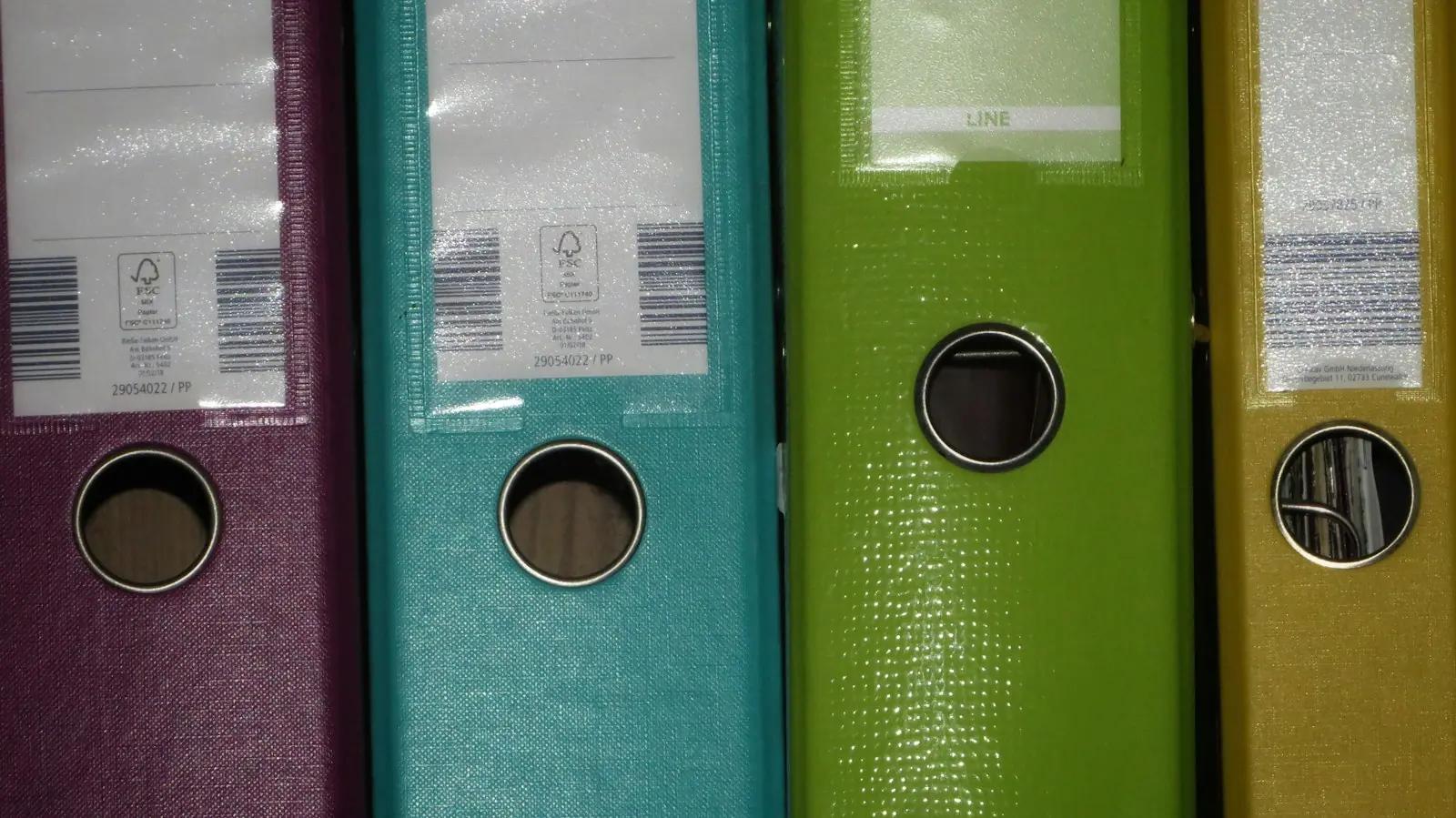 Spines of purple, teal, green and yellow ring binders