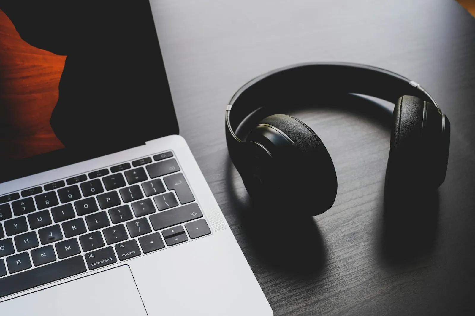 Black wireless headphones beside a laptop