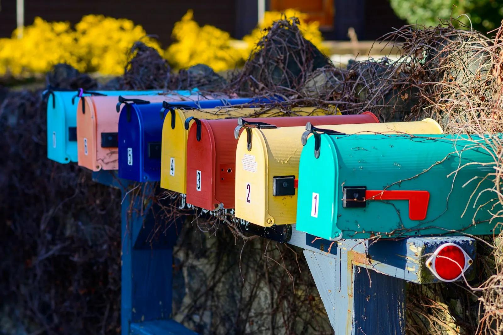A row of colorful mailboxes next to a bush