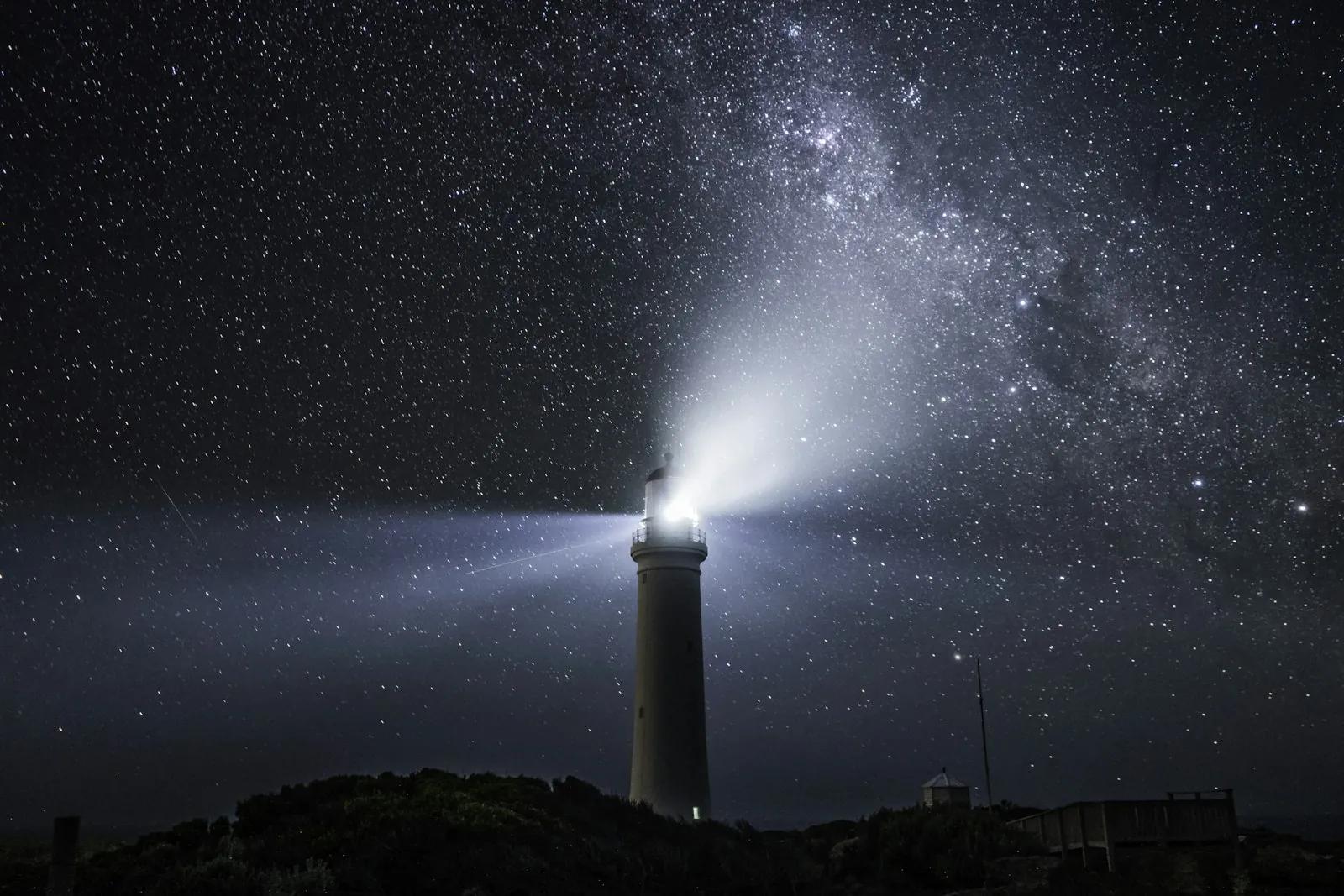 A lighthouse under a night sky full of stars
