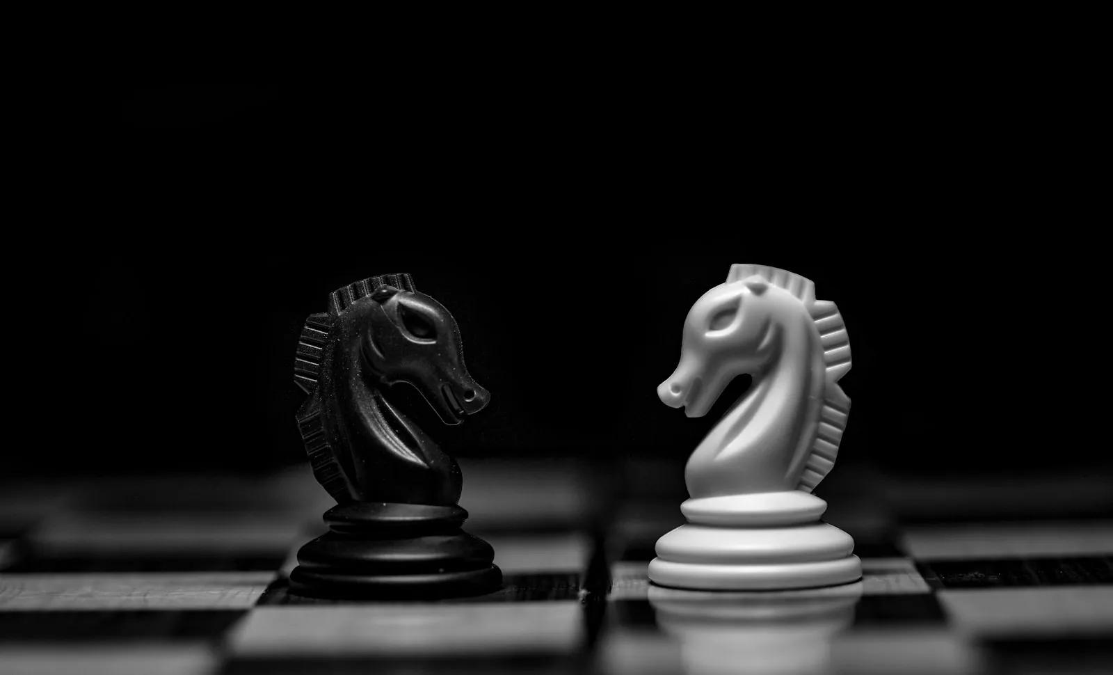 Black and white chess knights facing each other