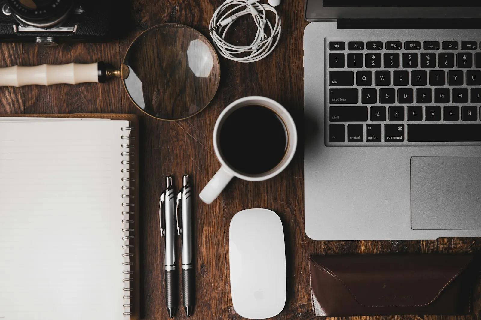 Cup of coffee next to a laptop on a desk