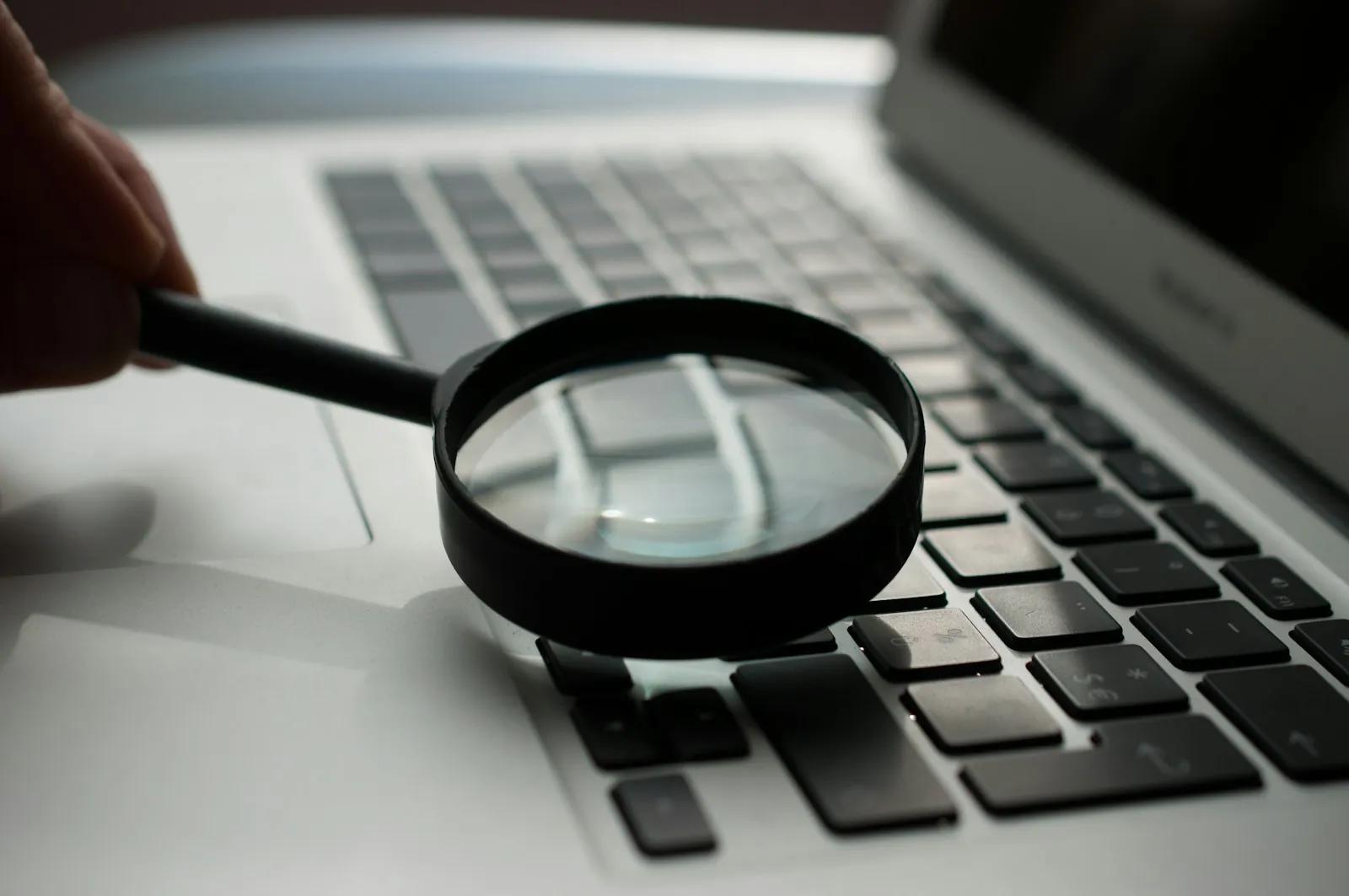 Magnifying glass next to a laptop