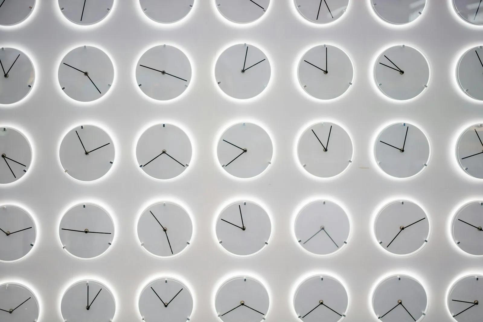 White wall covered with many clocks