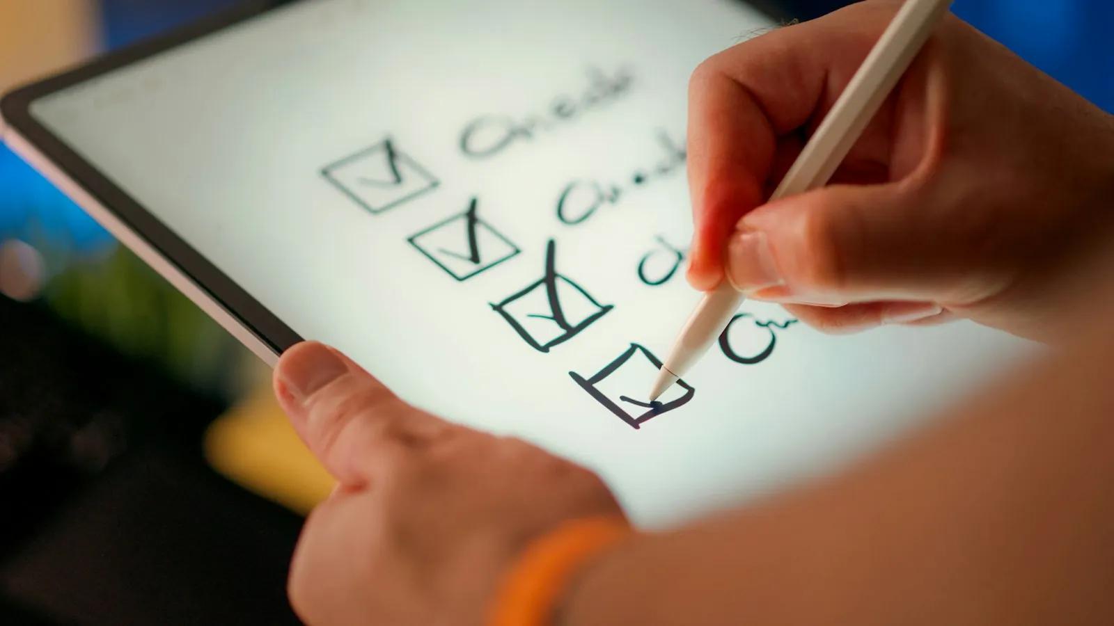 A hand ticking off items on a checklist with a stylus