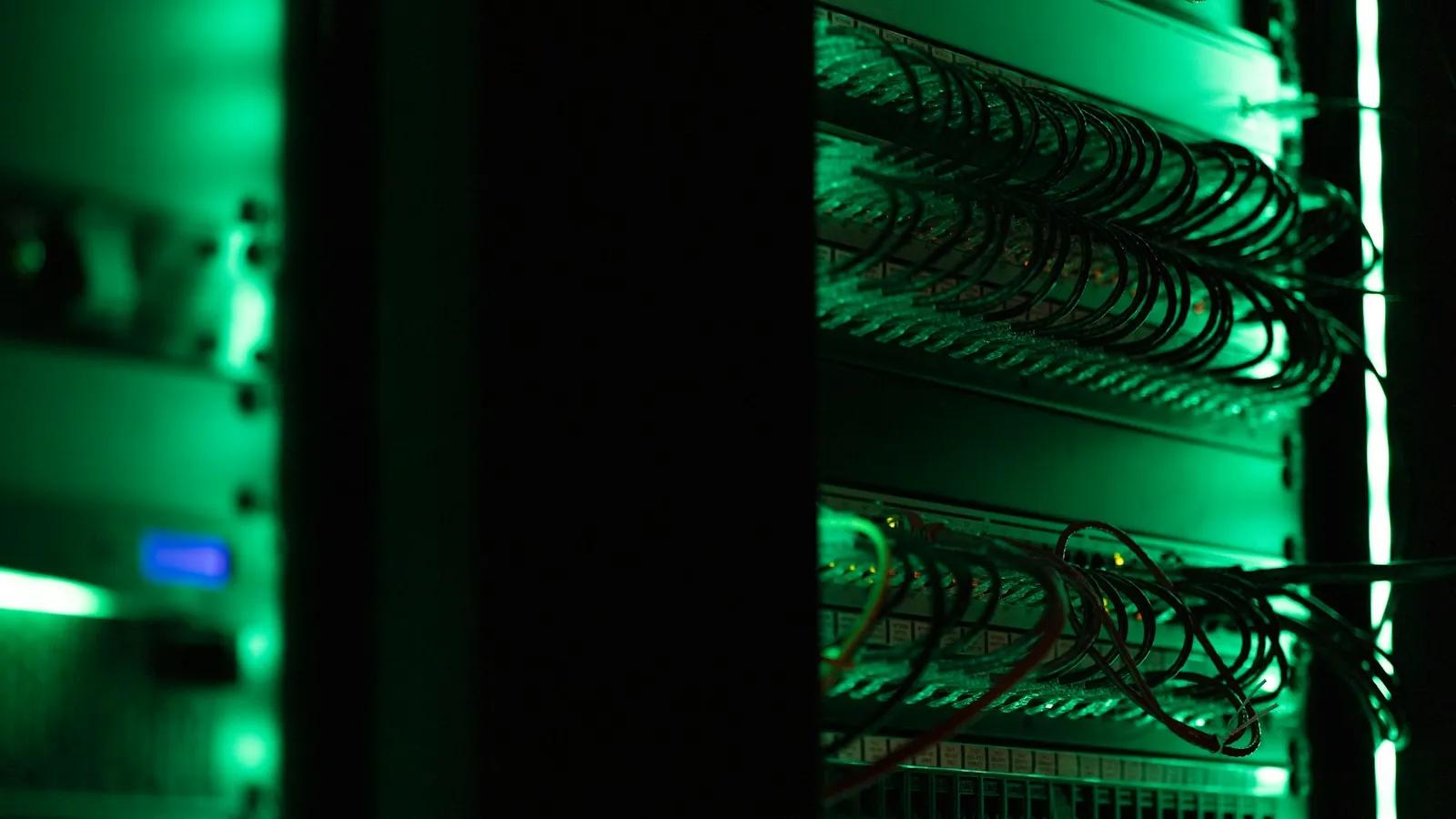 Server racks lit green in a dark room